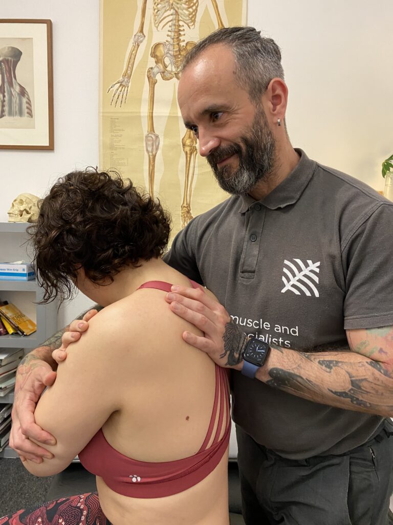 Jose Fernandez assessing a patient's shoulder in the clinic